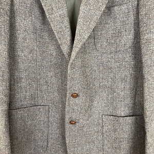 May include: A gray tweed blazer with two brown buttons and two flap pockets.