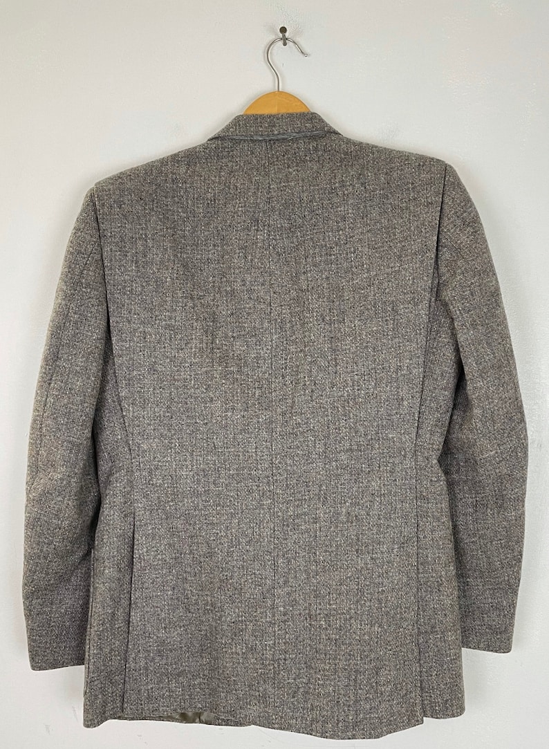 May include: A gray tweed blazer with a single button closure. The blazer has a classic fit and is made of a soft, comfortable fabric.