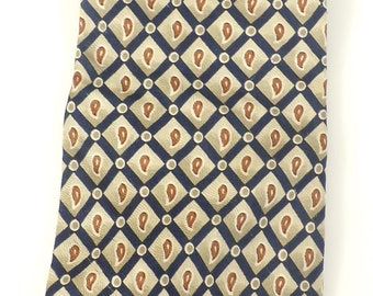 May include: A navy blue tie with a repeating pattern of tan paisley shapes and white circles. The paisley shapes are outlined in dark blue.