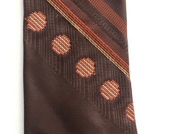 May include: A brown tie with a repeating pattern of small, white and orange floral shapes. Diagonal stripes in shades of brown and orange add visual interest. The tie is a classic accessory.
