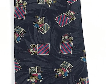 May include: A black silk tie with a repeating pattern of cartoon figures popping out of striped boxes. The figures are wearing red, yellow, and blue clothing.