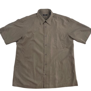 May include: A brown short-sleeved button-down shirt with a pocket on the left side.