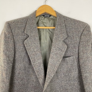 May include: A gray tweed blazer with a single button closure and a pocket on the left side. The label on the inside of the blazer reads "Pierre Cardin, Made in Hong Kong".