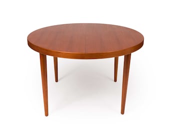 May include: A round, wooden dining table with a light brown finish and four slender legs. The table top is made of wood and has a smooth surface.