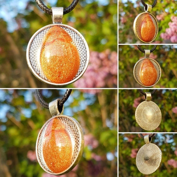 Silver amulet with a metallic bronze drop cast in transparent epoxy resin.