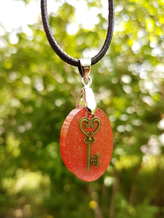 Necklace with oval pendant made of epoxy resin - bronze key with heart cast in metallic red and glitter