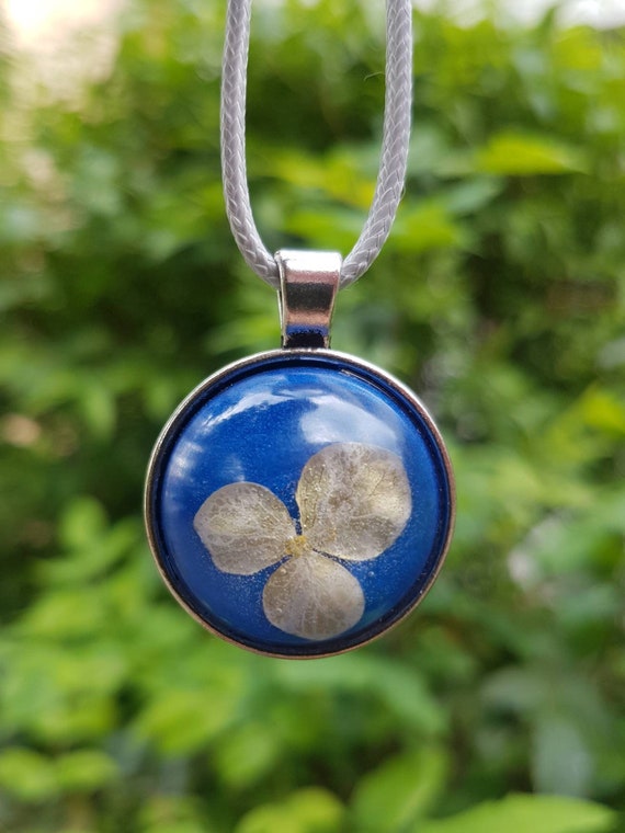 Kette mit rundem Anhänger - Amulett mit zarter Blüte in blauem Epoxidharz gegossen und Fassung in Silber