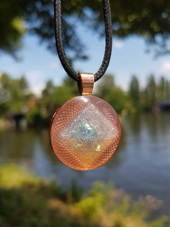Round amulet with a metallic silver hologram square in transparent epoxy resin.