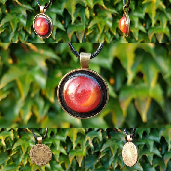 Necklace with a handmade pendant made of epoxy resin. Round bronze amulet with an eye of two moons in metallic red, silver, gold, and black.