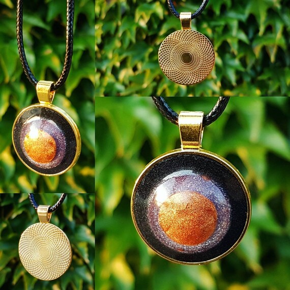 Necklace with a handmade pendant made of epoxy resin. Round amulet in gold with an interior in metallic bronze, silver-purple, and black.