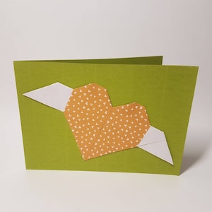 Carta pieghevole verde con cuore di origami arancione con ali bianche