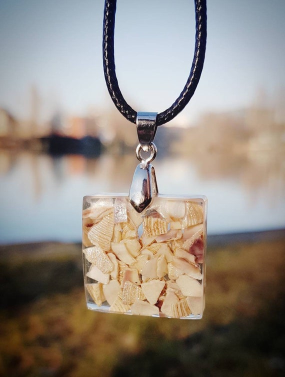 Necklace with pendant with slightly glittering shell fragments in transparent epoxy resin