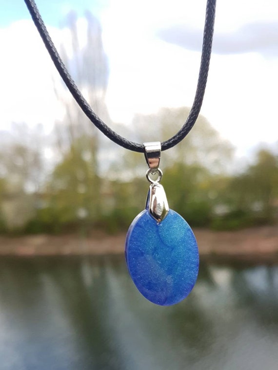 Necklace with oval pendant made of epoxy resin metallic: the depths of space in deep blue and purple with stardust