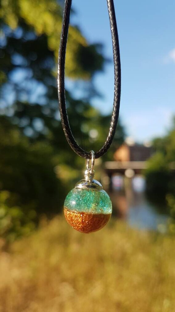 Kette mit Kugel Anhänger: klares türkis blaues und metallic bronzefarbenes Epoxidharz in mundgeblasener kleiner mini Glaskugel