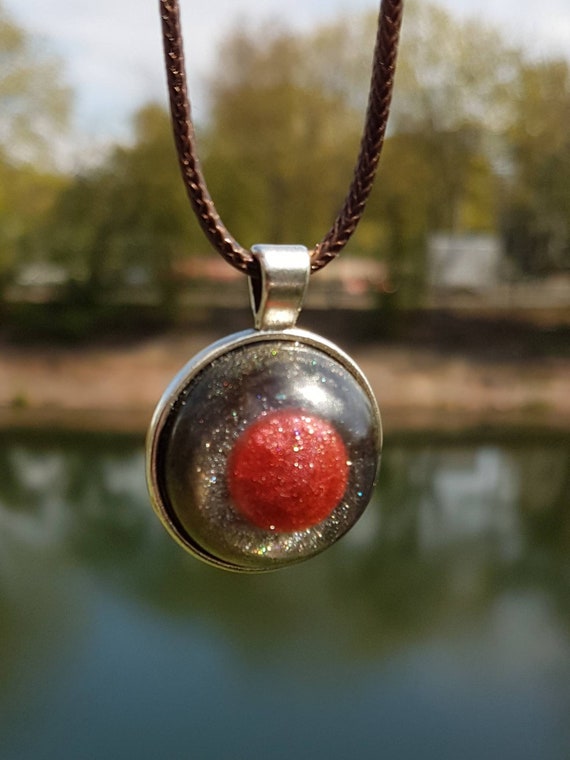 Necklace with round amulet pendant: metallic red circle cast in metallic black epoxy resin and setting in silver