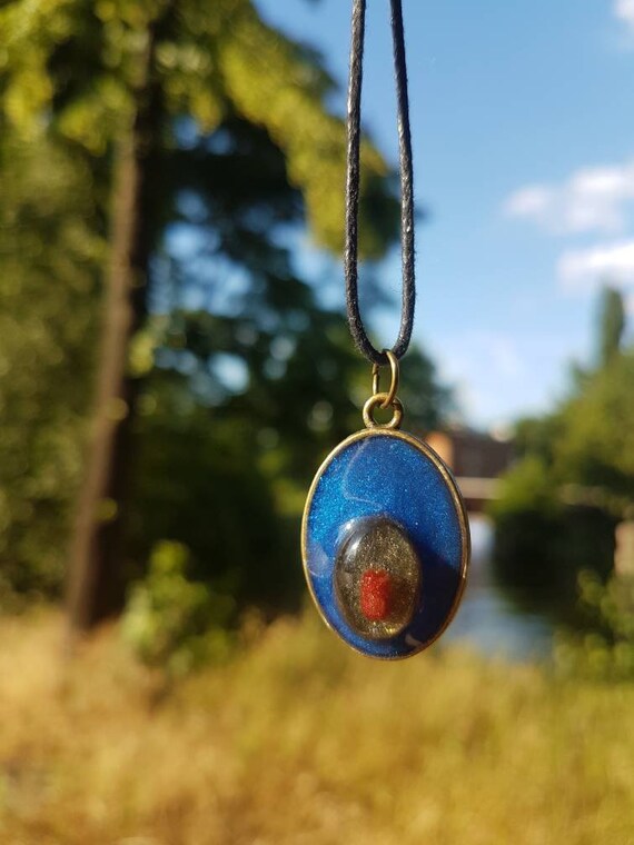 Kette mit ovalem Anhänger - Amulett aus metallic rotem, blauem und schwarzem Epoxidharz gegossen und Fassung in Bronze