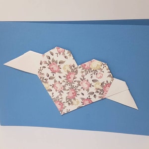 Blaue Klappkarte mit Origami-Herz mit kleinen Rosen und weißen Flügeln
