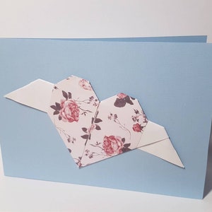 Carta pieghevole azzurra con rosa cuore origami con ali bianche