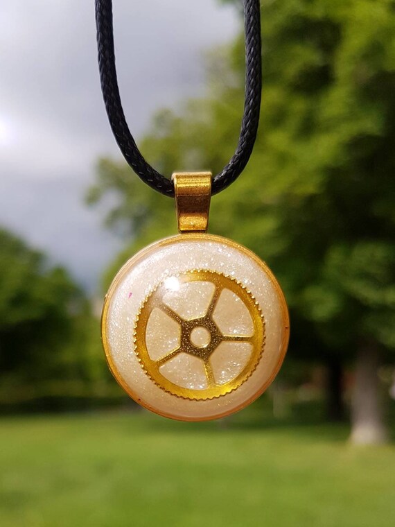 Necklace with round pendant: golden amulet with golden gear cast in metallic silver epoxy resin