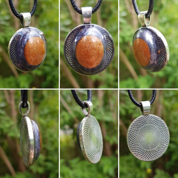 Round, silver amulet with oval interior - metallic bronze on silver-grey - cast in transparent epoxy resin.