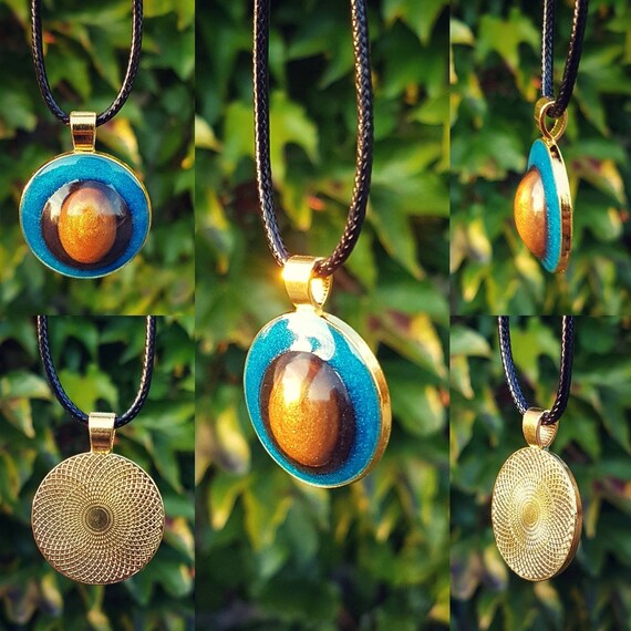 Necklace with a handmade pendant made of epoxy resin. Round amulet in gold with an interior in metallic blue, gold, and black.