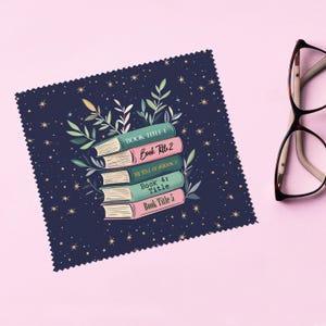 May include: A navy blue microfiber cleaning cloth with a stack of five books and gold stars. The books have titles that read "Book Title 1", "Book Title 2", "The Title of Book 3", "Book 4: Title", and "Book Title 5".