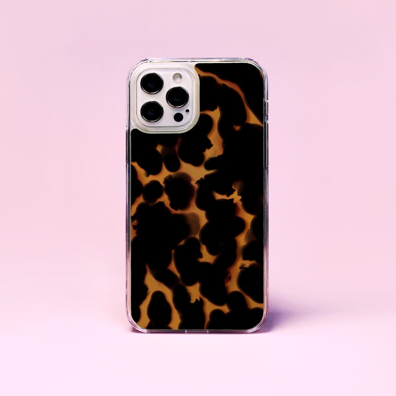 May include: A clear phone case with a brown and black tortoiseshell pattern. The case has a raised camera bump with three lenses.