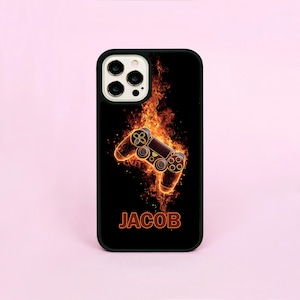 May include: Black phone case featuring a fiery video game controller design. The controller is outlined in orange and surrounded by flames. The name "JACOB" is displayed in orange at the bottom of the case.