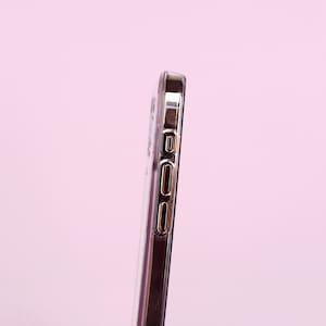 May include: A clear phone case with a gold trim around the edges. The case has cutouts for the phone's buttons and camera.