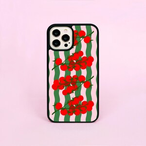 Peut inclure: Coque de téléphone noire avec un motif de tomates cerises rouges sur des tiges vertes sur un fond de rayures ondulées roses et vertes. La coque a une bordure noire et une découpe pour l'appareil photo.