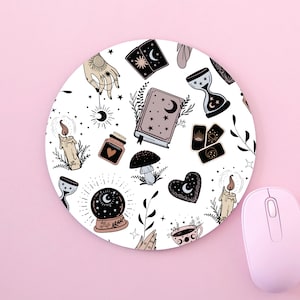 Könnte beinhalten: Rundes weißes Mauspads mit einem sich wiederholenden Muster mystischer Illustrationen. Das Design umfasst eine Kristallkugel, Tarotkarten, Kerzen, ein Buch und eine Hand mit einem Sonnentattoo. Eine rosa Computermaus befindet sich in der unteren rechten Ecke.