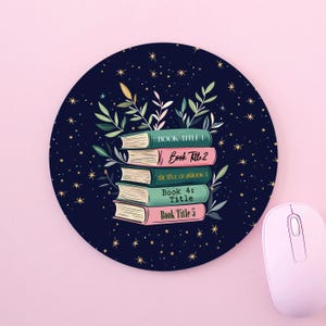 May include: A round mouse mat with a dark blue background and gold stars. A stack of five books with different coloured covers is in the centre of the mouse mat. The books have titles that say "Book Title 1", "Book Title 2", "The Title of Book 3", "Book 4: Title", and "Book Title 5".