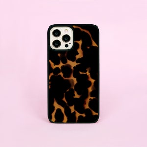 May include: A black phone case with a brown and black tortoise shell pattern. The case has a raised camera bump with three lenses.
