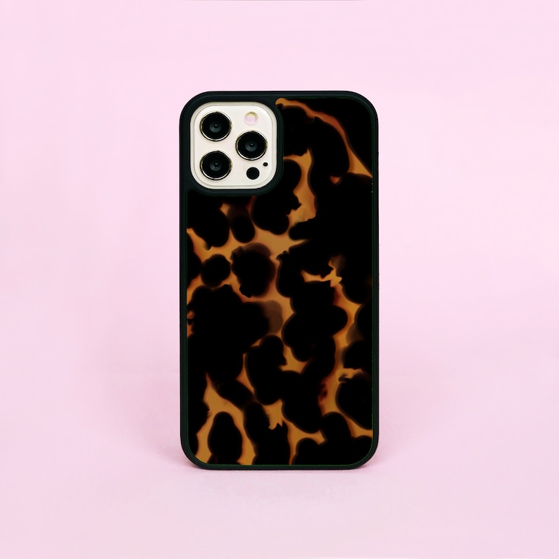 May include: A black phone case with a brown and black tortoise shell pattern. The case has a raised camera bump with three lenses.