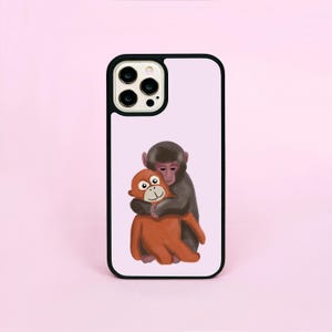 Könnte beinhalten: Schwarze Handyhülle mit hellviolettem Hintergrund. Sie zeigt eine Cartoon-Illustration von zwei sich umarmenden Affen. Ein Affe ist orange und der andere grau. Die Hülle hat einen schwarzen Rand und einen Kameraausschnitt.