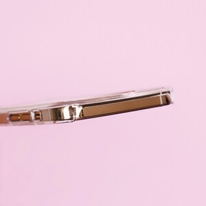 May include: A clear phone case with a rose gold metal bumper. The case is designed to protect a smartphone.