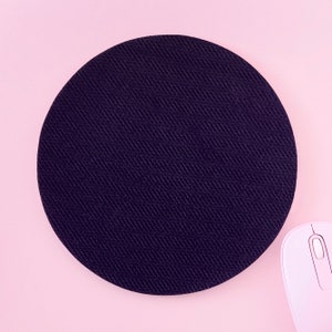 Peut inclure: Un tapis de souris rond noir sur un fond rose. Le tapis de souris a une surface textur&eacute;e.