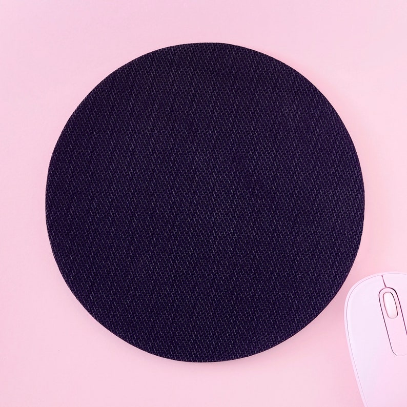Peut inclure: Un tapis de souris rond noir sur un fond rose. Le tapis de souris a une surface textur&eacute;e.