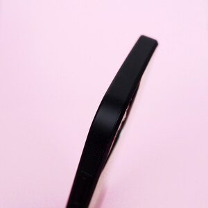 May include: Close-up of the side of a black phone case with a textured design.