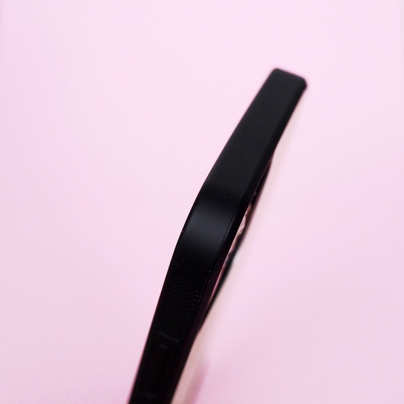 May include: Close-up of the side of a black phone case with a textured design.