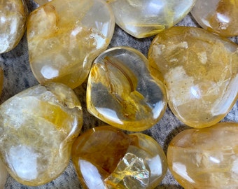 May include: A collection of heart-shaped citrine crystals, each with a unique golden hue and translucent appearance. The crystals are arranged in a close-up view, showcasing their natural beauty and intricate patterns.