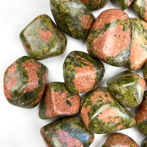 May include: A collection of tumbled green and red jasper stones. The stones are smooth and polished, with a variety of patterns and colors.