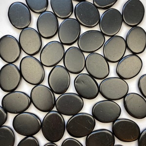 May include: A collection of smooth, black oval-shaped stones. The stones are polished and have a glossy finish.