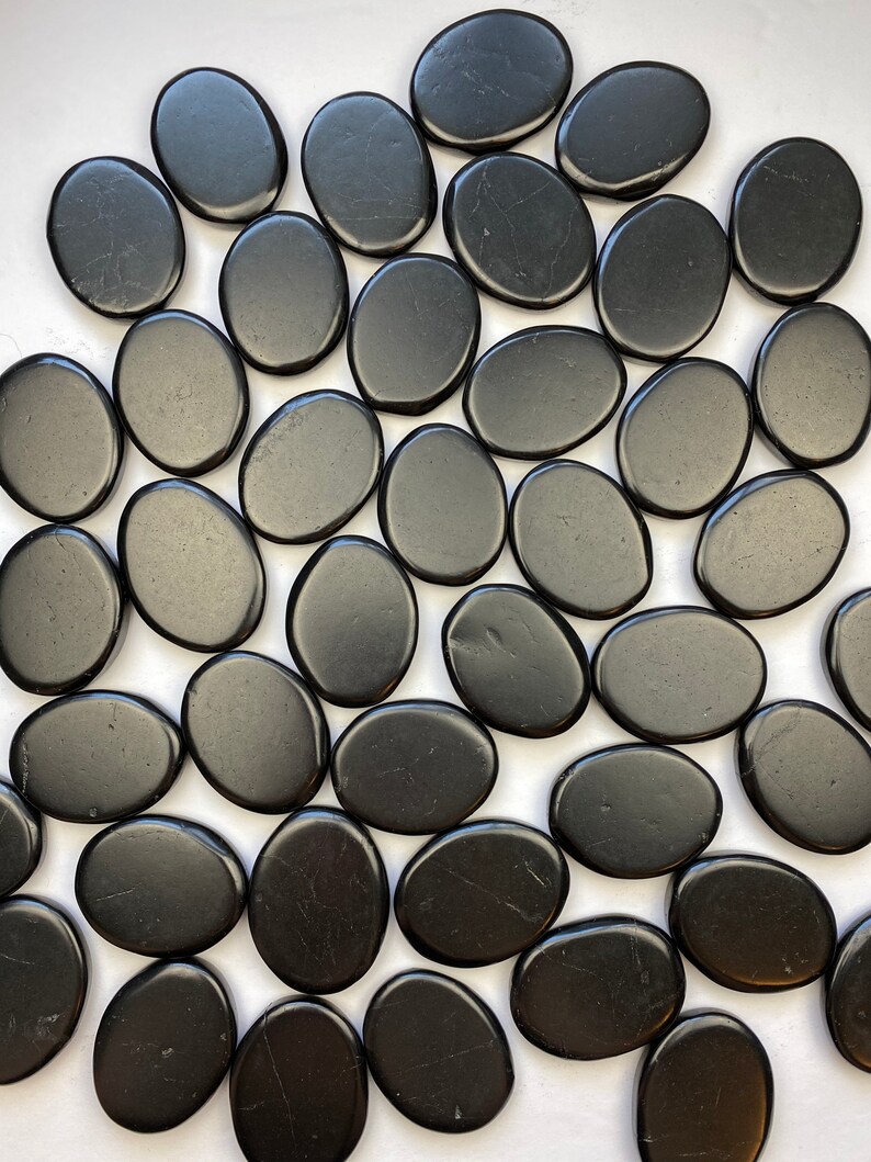 May include: A collection of smooth, black oval-shaped stones. The stones are polished and have a glossy finish.