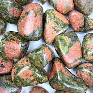 May include: A collection of tumbled green and red jasper stones. The stones are smooth and polished, with a variety of patterns and colors.