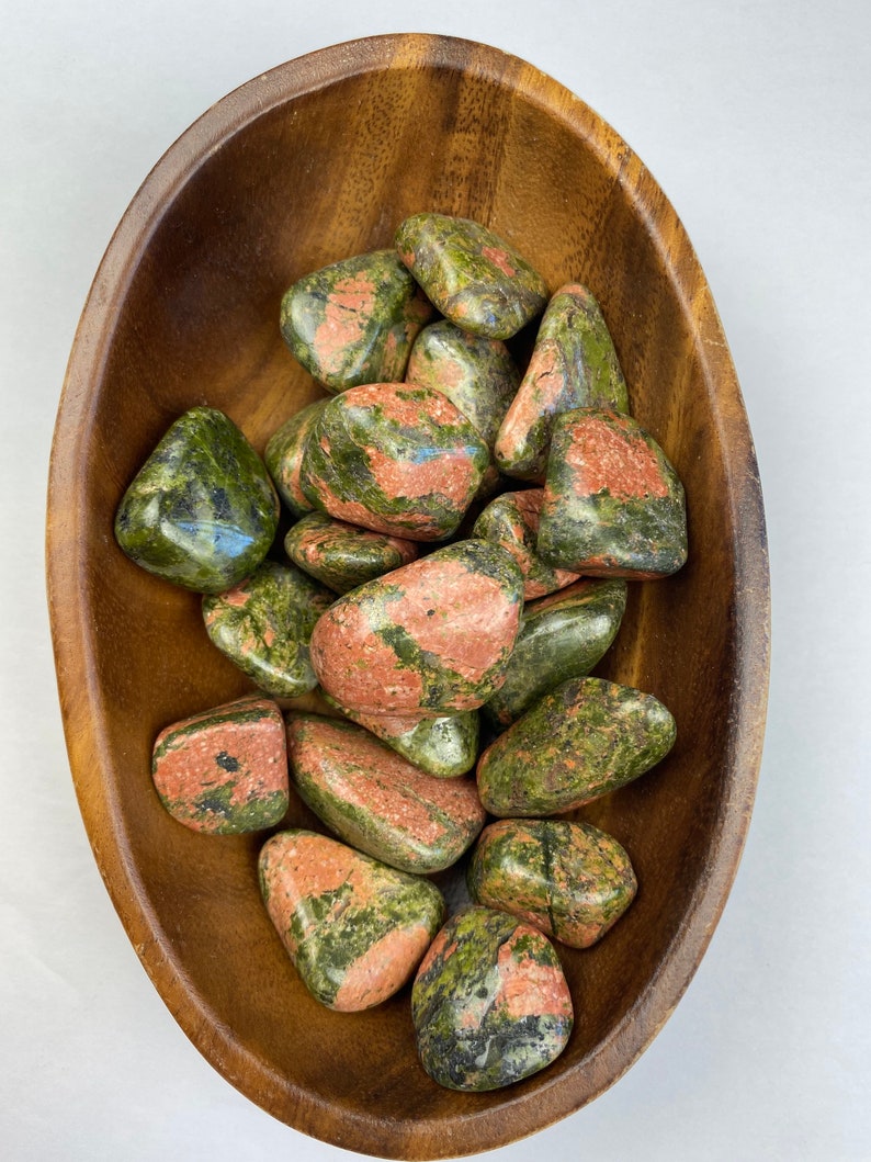 May include: A bowl of green and pink tumbled stones. The stones are smooth and polished, and they have a variety of shapes and sizes.