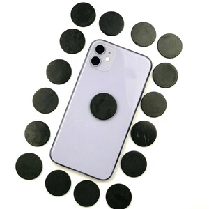 May include: A purple smartphone with a black magnetic phone ring holder surrounded by black round magnetic discs.