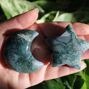 May include: A green and white agate moon and star set. The moon is crescent shaped and the star has five points. Both are polished and smooth.