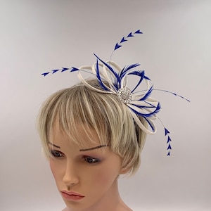 May include: A white and blue feather hair comb with a rhinestone embellishment. The comb is designed for a wedding or special occasion.