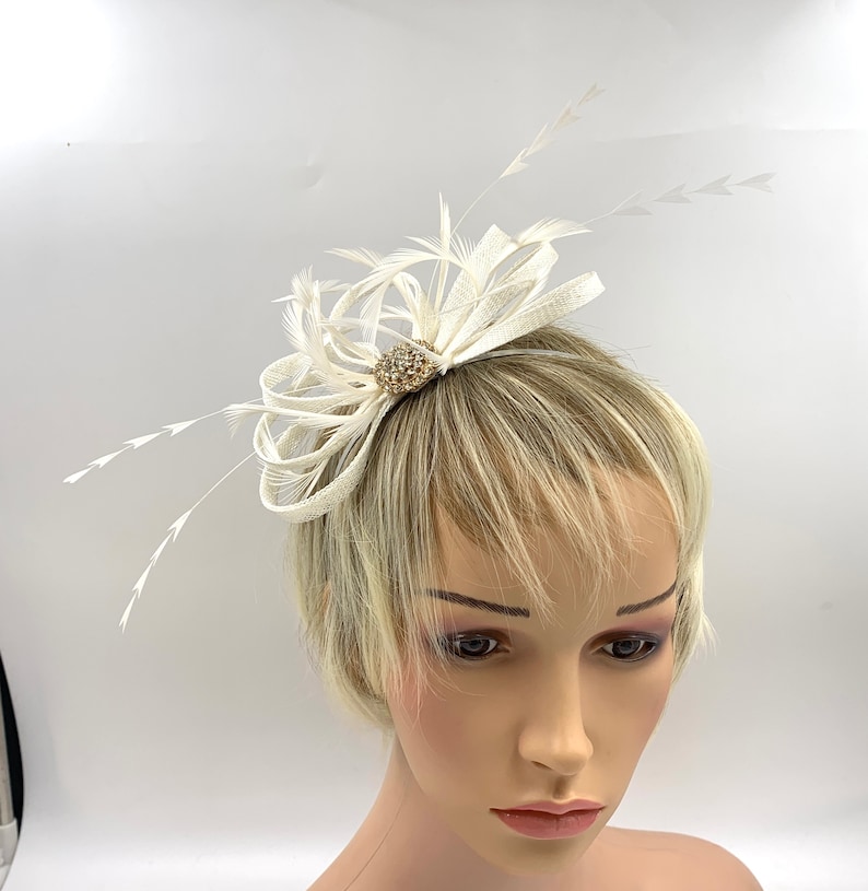 Pode incluir: Um pente de cabelo de penas brancas com um enfeite de strass. O pente &eacute; projetado para um casamento ou ocasi&atilde;o especial.
